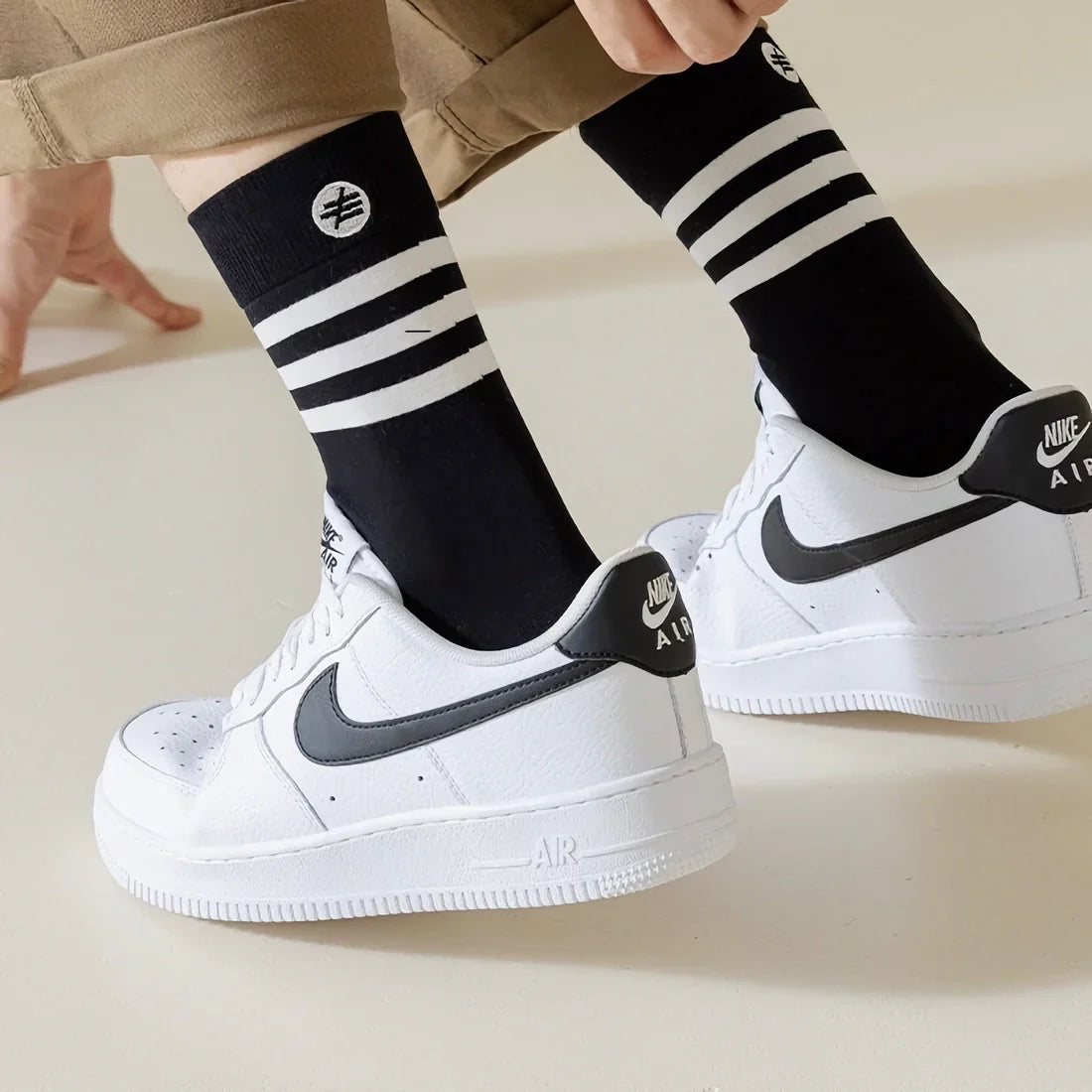 The image shows a person wearing a pair of black socks with three white stripes around the top of the sock.